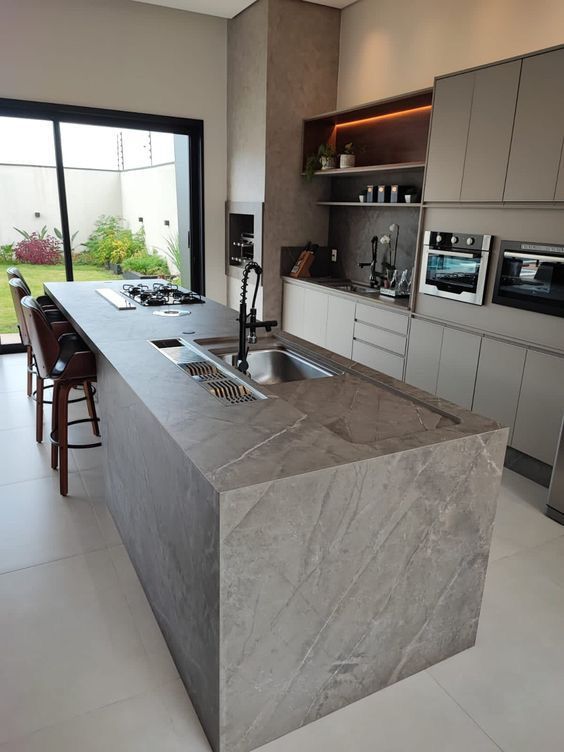 Kitchen with a stone-clad island, waterfall edge and large-format floor tile