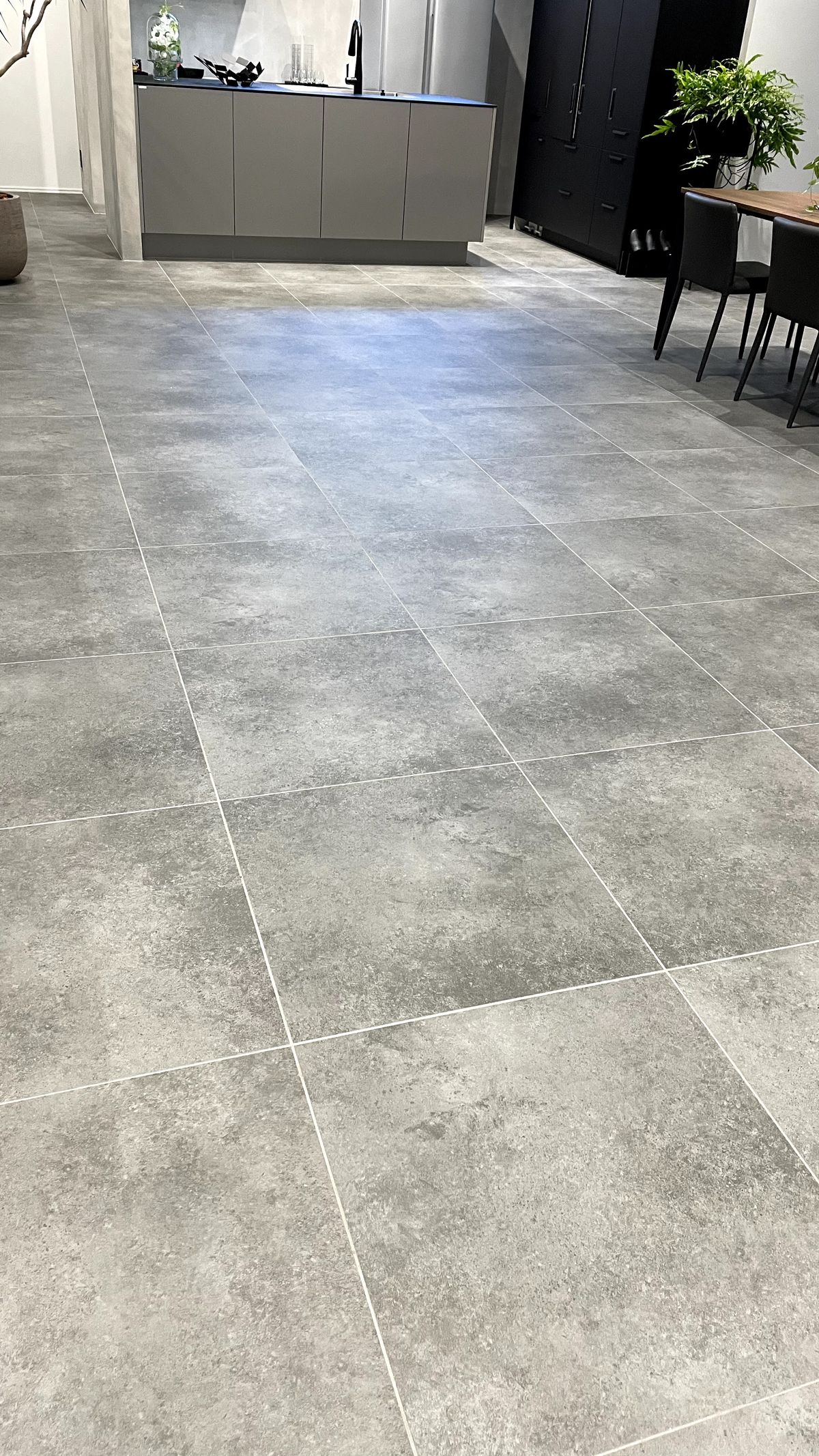 Large-format gray porcelain floor tile running through an open-plan kitchen and dining area